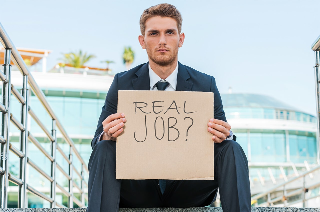 A finance employee holds a sign asking if a job is real